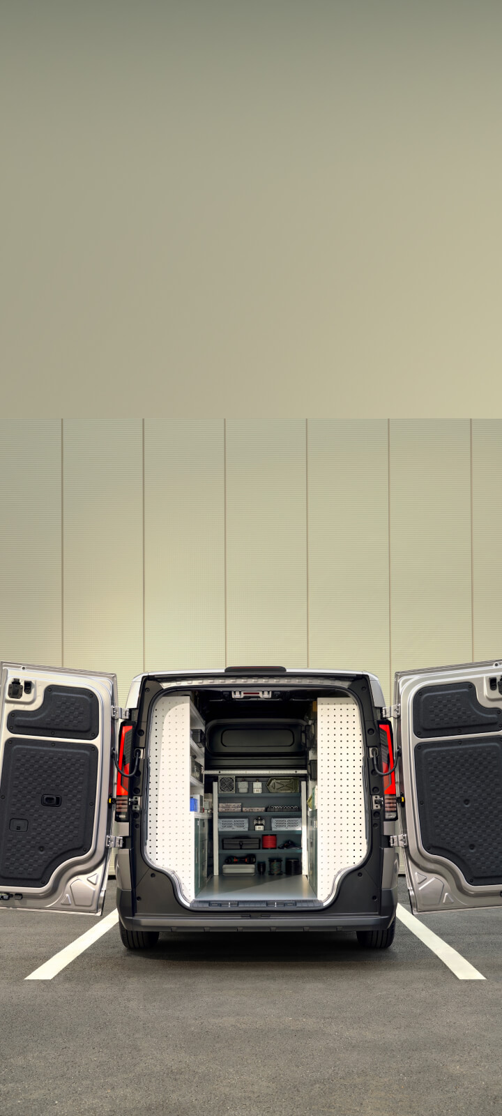 Mitarbeiterin mit Werkzeugkoffer neben dem geöffneten Laderaum des Kia PV5 Cargo.